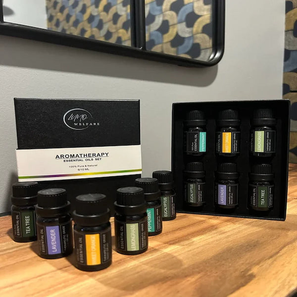 Coffret 6 huiles essentielles LUNO Welfare (lavande, orange douce, tea tree, citron, eucalyptus, menthe poivrée) posé sur meuble bois, ambiance chaleureuse.